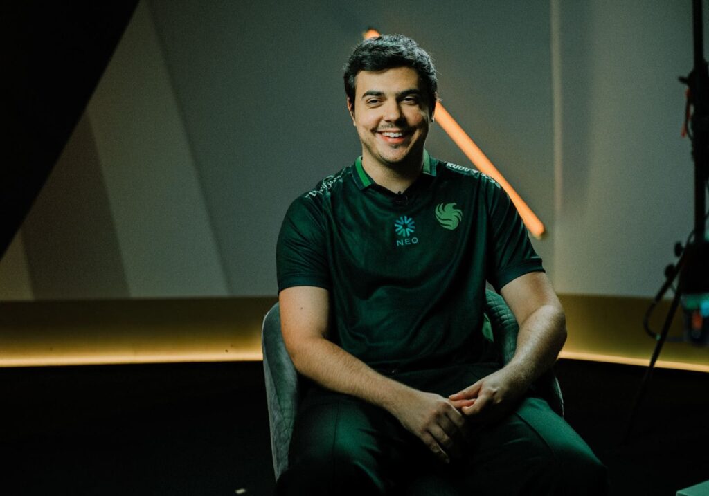 ImperialHal in a green sports jersey sits in a modern, well-lit studio, with abstract geometric shapes and warm lighting in the background.