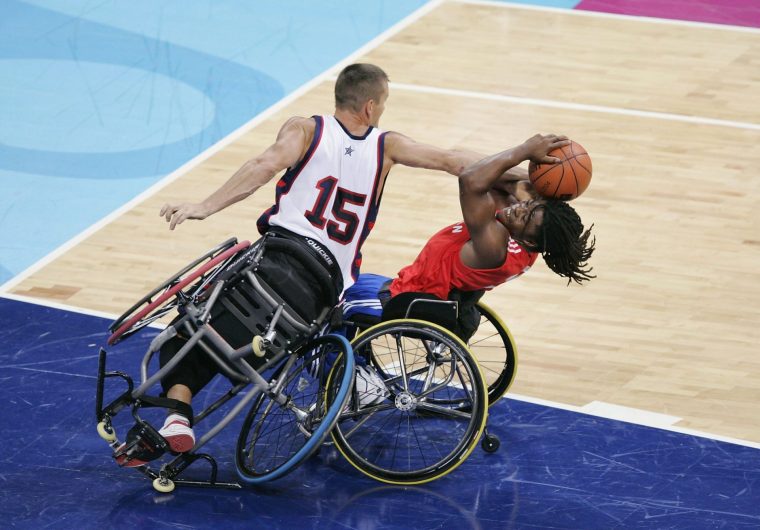 ATHENS - SEPTEMBER 25: Ade Adepitan #10 of Great Britain gets fouled by Jeff Glasbrenner #15 of the USA with the score tied and 7.1 seconds left in the game during the quarterfinals of wheelchair basketball on September 25, 2004 during the 2004 Paralympic Games in Athens, Greece. Britain won on the Adepitan's free throws. (Photo by Brian Bahr/Getty Images)