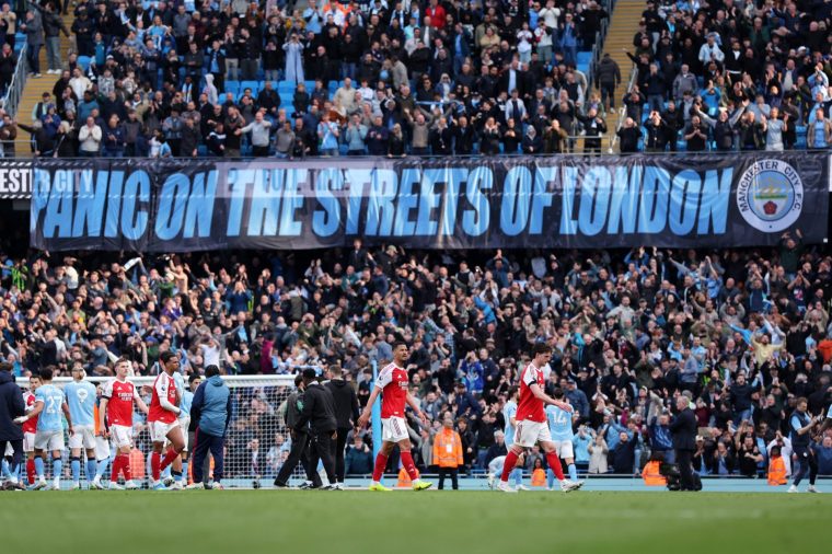 MANCHESTER, ENGLAND - APRIL 19: Declan Rice, William Saliba and Gabriel of Arsenal walk off dejected under a banner which reads 'Panic on the streets of London' following the Premier League match between Manchester City and Arsenal at Etihad Stadium on April 19, 2026 in Manchester, England. (Photo by Alex Livesey - Danehouse/Getty Images)