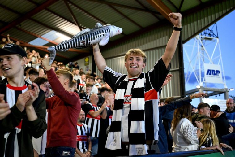 GRIMSBY, ENGLAND - AUGUST 27: Grimsby Town fan celebrates victory following the penalty shoot out during the Carabao Cup Second Round match between Grimsby Town and Manchester United at Blundell Park on August 27, 2025 in Grimsby, England. (Photo by Shaun Botterill/Getty Images)