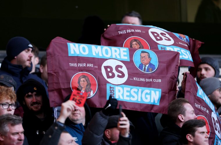 WOLVERHAMPTON, ENGLAND - JANUARY 03: West Ham United fans hold up No More BS Just resign flags featuring caricatures of Karren Brady and David Sullivan as they protest against the ownership during the Premier League match between Wolverhampton Wanderers and West Ham United at Molineux on January 03, 2026 in Wolverhampton, England. (Photo by Michael Regan/Getty Images)